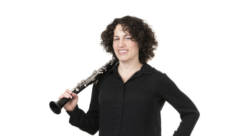 Kiharahiuksinen nainen hymyilee ja pitelee olallaan klarinettia. Kuva Jiri Halttunen