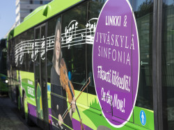 Vihreän linja-auton kyljessä näkyy viulisti sekä nuottiviivasto. Kuva Jiri Halttunen