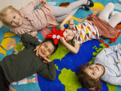 Neljä lasta on selällään värikkäällä matolla. Kuva Hanna-Kaisa Hämäläinen